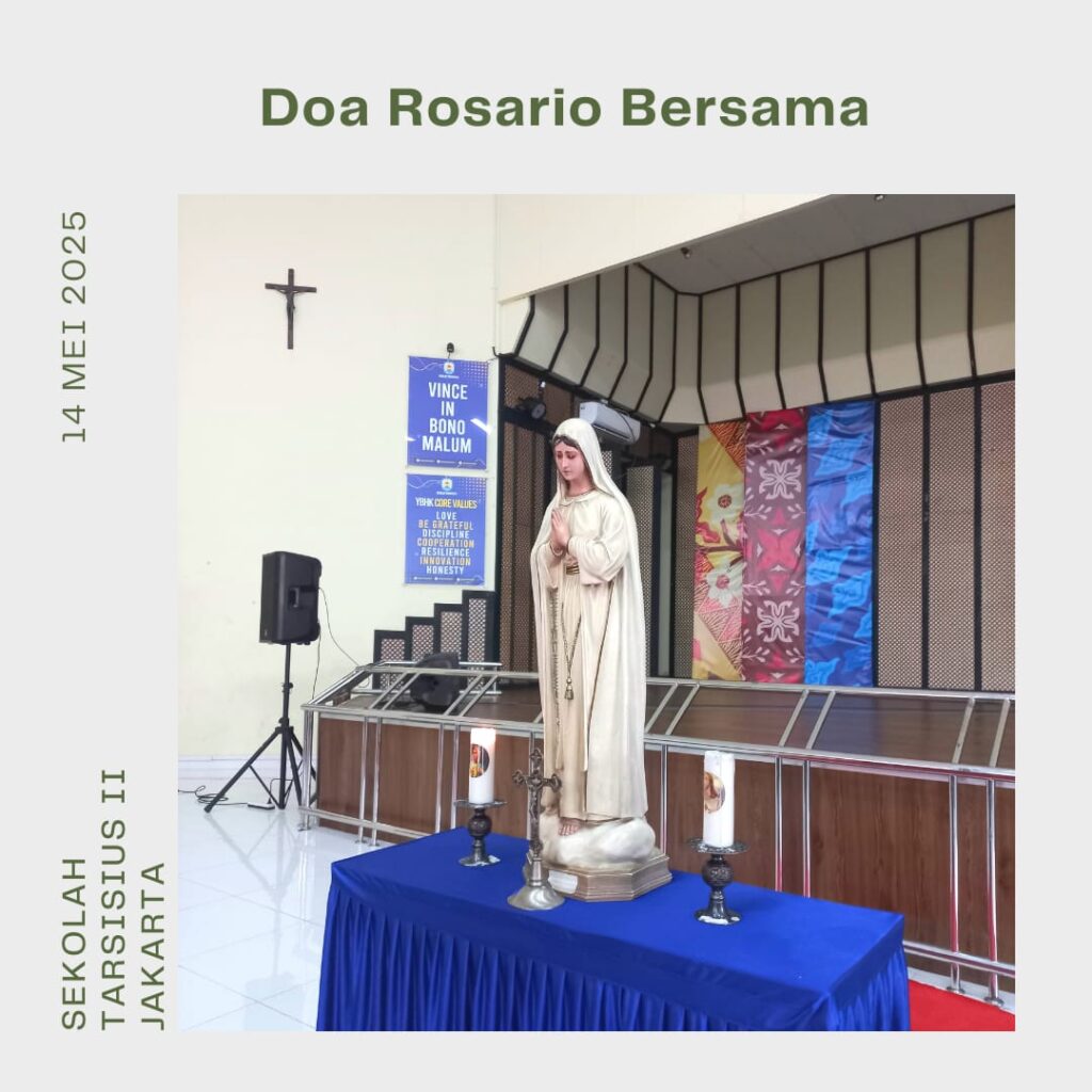 Foto suasana doa Rosario di Aula SMA Tarsisius. Para siswa duduk hening dalam barisan teratur, sebagian memegang rosario. Di depan altar, Keyla, siswi kelas XI, memimpin doa dengan tenang. Terdapat salib dan lilin menyala di meja altar sebagai simbol sakralitas doa.